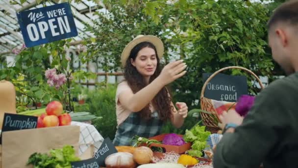 Přátelská prodejní žena prodávajících potraviny mužským zákazníkům, kteří berou peníze na trh — Stock video