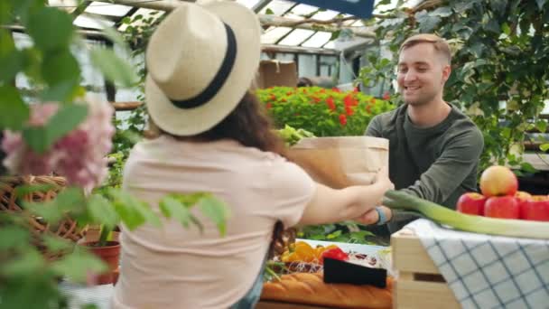 Customers buying organic food in greenhouse sale talking to shop assistant — Αρχείο Βίντεο