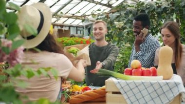 Pazarda organik gıda seçen bir grup müşteri satış elemanıyla konuşuyor