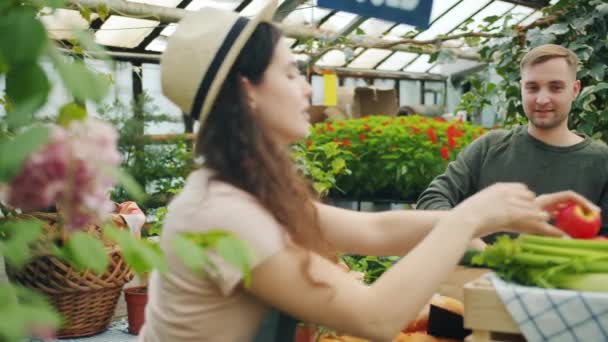 Chico feliz comprando comida orgánica en el mercado y luego dando dinero en efectivo a la chica de ventas — Vídeo de stock