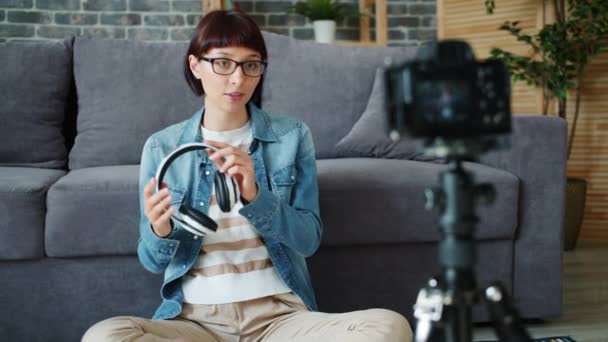 Gadget especialista em gravação de vídeo sobre novos fones de ouvido falando para a câmera em casa — Vídeo de Stock