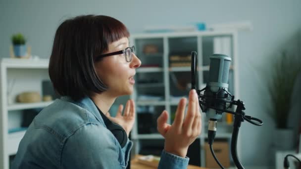 Chica alegre en gafas hablando en micrófono sonriente grabación de audio podcast — Vídeos de Stock