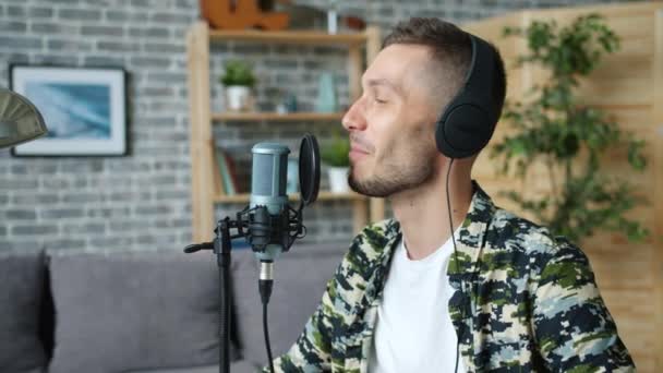 Cámara lenta del hombre feliz en auriculares hablando en micrófono en el estudio de grabación — Vídeo de stock