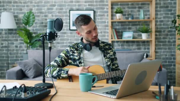 Красивый парень играет на гитаре аудио в студии с помощью микрофона — стоковое видео