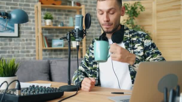 Wesoły człowiek cieszy się kawą i nagrywanie audio podcast w nowoczesnym studiu — Wideo stockowe