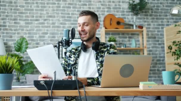 Lento movimiento de feliz blogger grabación podcast lectura en el micrófono en el interior — Vídeo de stock