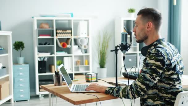 Komoly fiatalember felvétel podcast mikrofonnal és laptoppal beszélgetett stúdióban — Stock videók