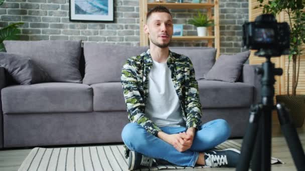 Vlogger Przemawiając do kamery pokazując kciuki-up siedzi na podłodze w domu — Wideo stockowe
