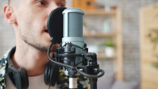 Zeitlupe eines glücklichen jungen Mannes, der im Studio lächelnd in Mikrofon spricht — Stockvideo