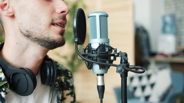 Jeune beau mec enregistrement podcast parler dans microphone souriant en studio — Video