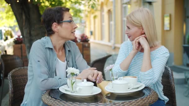 Cámara lenta de señoras maduras socializando en café al aire libre hablando riendo — Vídeos de Stock