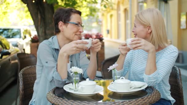 Volwassen dames koffie drinken en praten in open lucht café op zomerdag — Stockvideo