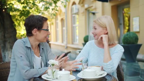 Female friends having good time in street cafe talking laughing sitting at table — Stock Video