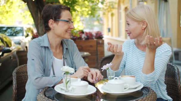 Glada kvinnor skrattar prata ha kul att koppla av i gatukafé på sommardag — Stockvideo