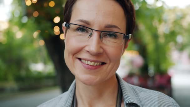 Portrait of cheerful brunette in glasses smiling outdoors looking at camera — Stock Video