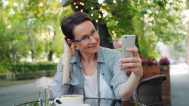 Sadece açık hava kafede rahatlatıcı poz akıllı telefon ile selfie çeken güzel bayan