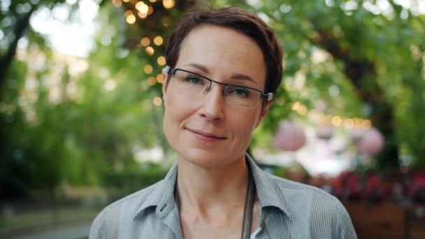 Slow motion portrait of elegant woman in glasses smiling outdoors in summer — Stock Video