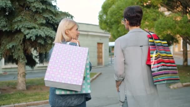 Retrato de damas felices caminando al aire libre con bolsas girando a la cámara sonriendo — Vídeo de stock