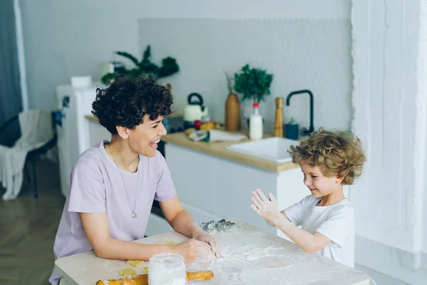 Madre e hijo se divierten con la harina cocinando galletas caseras en la cocina — Foto de Stock