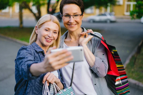 Πορτρέτο του Happy γυναίκες φίλοι λήψη selfie σε εξωτερικούς χώρους με σακούλες για ψώνια — Φωτογραφία Αρχείου