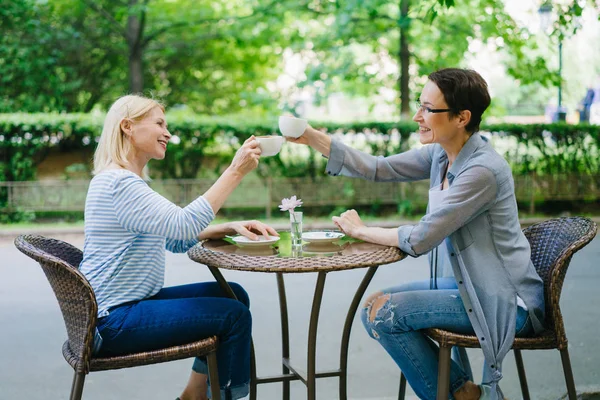 Hermosas señoras alegres tazas de té clanging hablando en la cafetería al aire libre — Foto de Stock