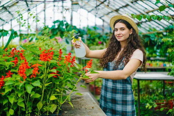 Портрет красивой девушки-фермера с использованием баллончика в теплице поливая цветы — стоковое фото
