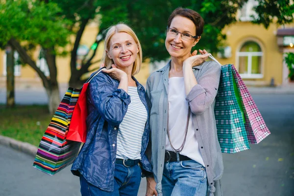 Portret van mooie volwassen dames houden boodschappentassen glimlachend buitenshuis — Stockfoto