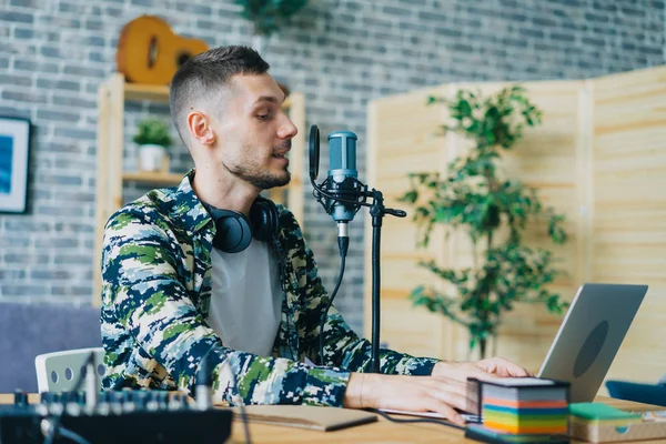 Cara usando microfone e laptop falando podcart gravação no apartamento — Fotografia de Stock