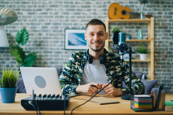 Retrato de jovem blogueiro em estúdio de gravação perto do microfone sorrindo — Fotografia de Stock