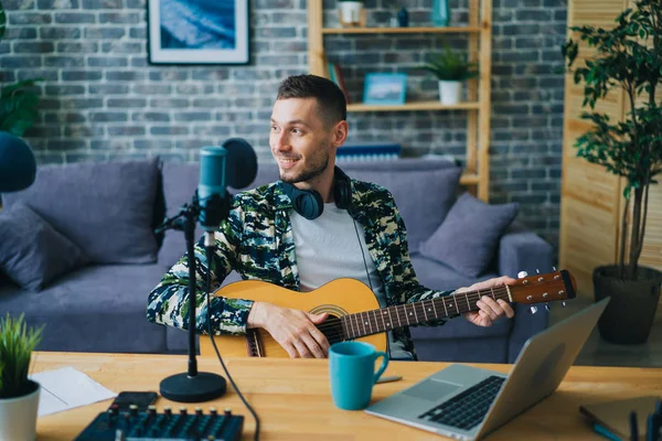 Pohledný chlápek hrající na kytaru záznam zvuku ve studiu pomocí mikrofonu — Stock fotografie