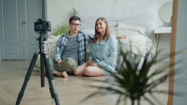 Дівчина і хлопець відеоблогери кодують відео для відеоблогу, показуючи великі пальці, що говорять вдома — стокове відео