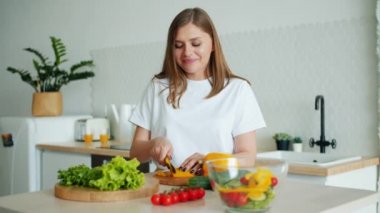 Genç ev hanımı mutfakta bıçak ile biber dilimleme salata pişirme Portresi