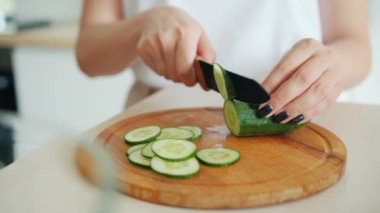Mutfakta bıçakla salatalık kesen kadın ellerinin yakın çekim yavaş hareketi