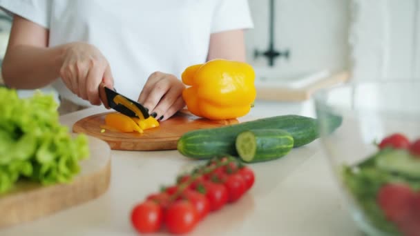 Main féminine tranchant du poivre frais avec une salade de cuisine au couteau à la maison dans la cuisine — Video