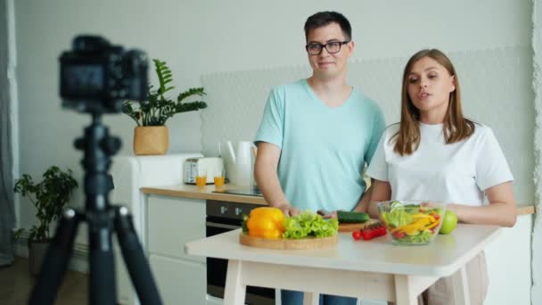 Casal de blogueiro gravação de vídeo na cozinha mostrando polegar-up acenando mão — Vídeo de Stock