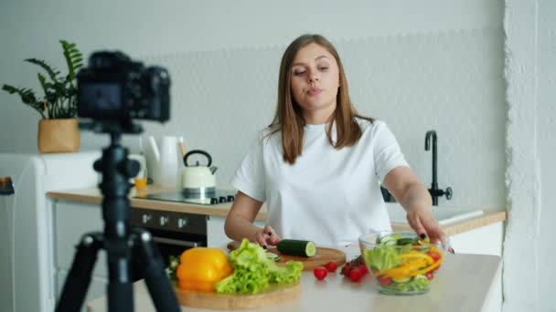 Vonzó lány vlogger felvétel videó a konyhában bemutató zöldségek főzés — Stock videók