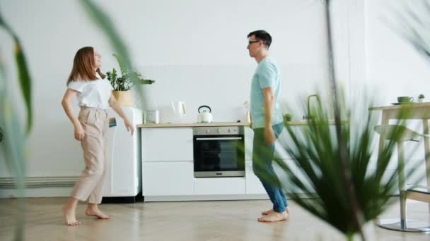 Jong meisje en kerel met plezier in de keuken thuis dansen lachen samen — Stockvideo