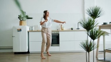 Neşeli genç kadın evde dans kulaklık ile müzik dinliyor