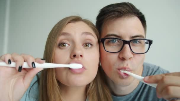 Крупным планом портрет счастливых молодых людей, чистящих зубы, улыбающихся, глядя в камеру — стоковое видео