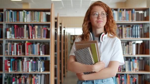 Slow Motion van mooi meisje wandelen in school bibliotheek met boeken rondkijken — Stockvideo