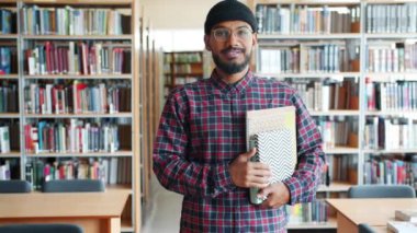 Kütüphanede kitap tutan neşeli Afrikalı-Amerikalı yetişkin öğrencinin yavaş hareketi