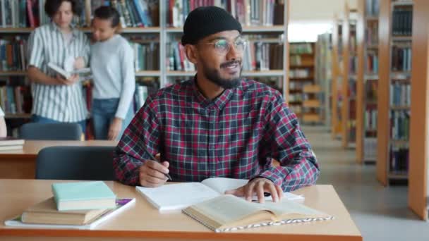 African American student learning in library reading writing sitting at desk — Stock Video