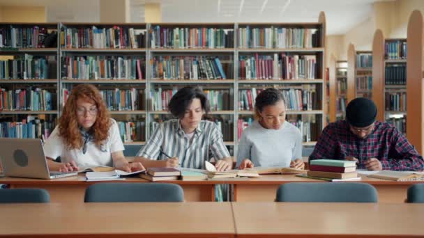 Πορτραίτο των πολυάσχολων φοιτητών νεολαίας που σπουδάζουν στη βιβλιοθήκη διαβάζοντας βιβλία γράφοντας σημειώσεις — Αρχείο Βίντεο