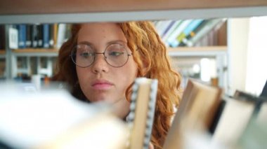 Gözlük pretty kız ciddi bir yüz ile kitapçı okuma kitap seçerek