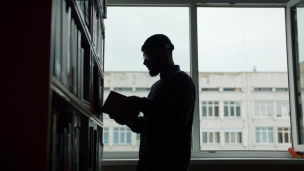 Hombre afroamericano tomando libro de estante en lectura de biblioteca universitaria — Vídeo de stock