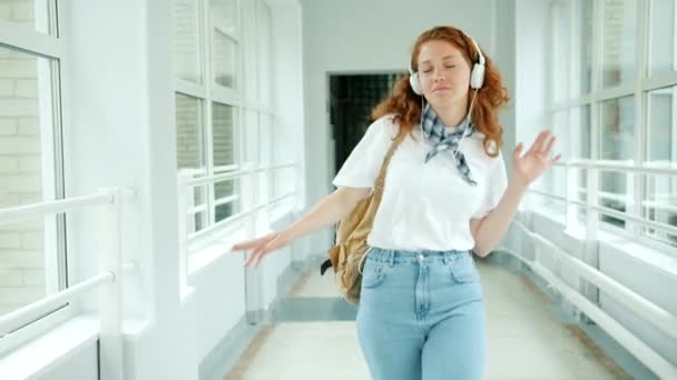 Χαρούμενος έφηβος στα ακουστικά απολαμβάνοντας τη μουσική χορεύοντας στο σχολικό αίθουσα με διασκέδαση — Αρχείο Βίντεο