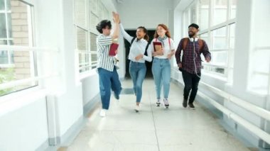 Üniversite salonunda koşan öğrencilerin yavaş hareketi gülerek beş atlama yapıyor