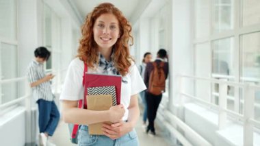 Üniversite salonunda gülümseyen kitap tutan çekici genç kız portresi