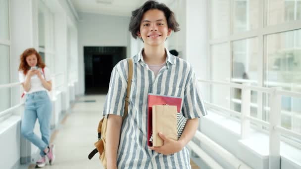 Retrato de niño alegre de pie en la sala de la universidad sonriendo mirando a la cámara — Vídeos de Stock