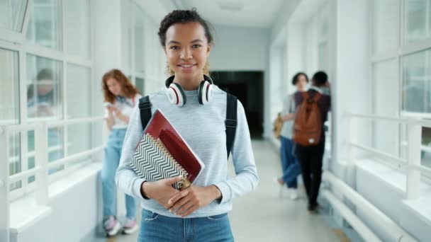 Rallentatore di bella afroamericano ragazza in piedi in scuola sala con libri — Video Stock